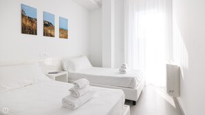 Una habitación de hotel con dos camas, una mesita de noche y un aire acondicionado de pared.