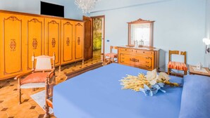 A bedroom with a large bed, wooden wardrobe, and a mirror. - Belvilla by OYO Appartamento Spinesante (Barcellona Pozzo di Gotto)
