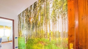 A hallway with a wooden door and a wall mural of a forest scene. - Belvilla by OYO Appartamento Spinesante (Barcellona Pozzo di Gotto)