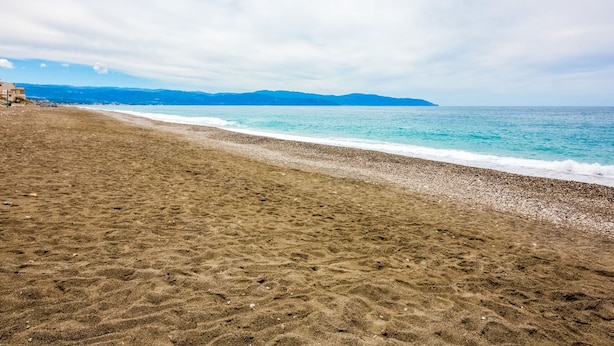 A beach with a pebble shore and a view of the sea and distant mountains. - Belvilla by OYO Appartamento Spinesante (Barcellona Pozzo di Gotto)