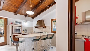 A kitchen with a central island, bar stools, a microwave, oven, and a red cabinet. - Valley View Villa in San Mango D'aquino with Hot Tub (San Mango d'Aquino)