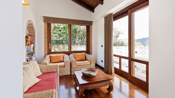 A spacious living area with wicker furniture, a wooden coffee table, and large windows offering a view of the outdoors. - Valley View Villa in San Mango D'aquino with Hot Tub (San Mango d'Aquino)