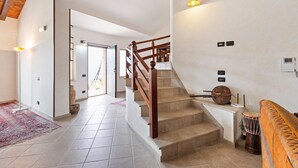 A spacious hallway with a wooden staircase, a patterned rug, and a drum set. - Valley View Villa in San Mango D'aquino with Hot Tub (San Mango d'Aquino)