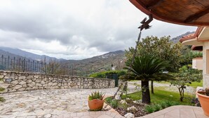 A stone patio with potted plants, a stone wall, and a view of mountains. - Valley View Villa in San Mango D'aquino with Hot Tub (San Mango d'Aquino)