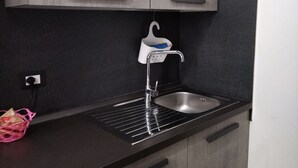 A kitchen with a stainless steel sink, a black countertop, and grey cabinets. - Belvilla by OYO La Casa di Giada (Belpasso)