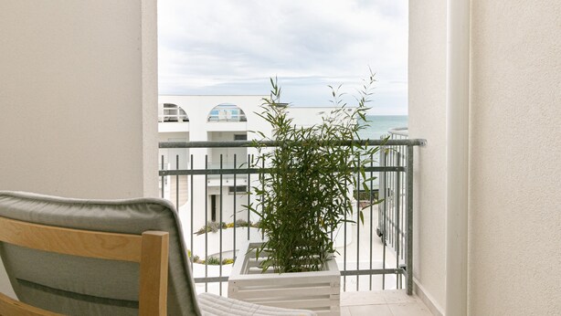 A balcony with a view of the sea, a chair, and a potted plant. - Rivazzurra Homes - 59 (Termoli)