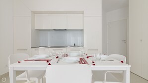 A modern, white dining area with a kitchen in the background. - Rivazzurra Homes - 59 (Termoli)