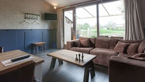 Ein Zimmer mit einer Couch, einem Tisch und einem an der Wand befestigten Fernseher.