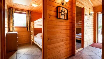Eine Holzhütte mit Etagenbett, Schreibtisch und einem Fenster mit Vorhängen.