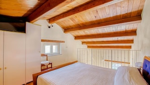 A bedroom with a wooden ceiling, a bed, a window, and a wardrobe. - Belvilla by OYO Casa Cerbaia Ciliegio (Pennabilli)