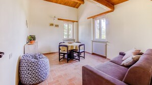 A cozy room with a wooden ceiling, a dining table with chairs, a purple sofa, and a patterned ottoman. - Belvilla by OYO Casa Cerbaia Ciliegio (Pennabilli)
