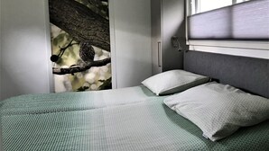 Une chambre à coucher avec un lit, une fenêtre et un mur décoré d’une œuvre représentant une branche d’arbre.