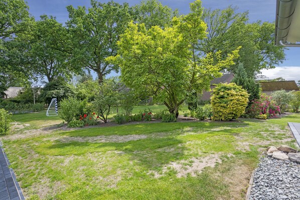 A well-maintained garden with various trees and shrubs, a lawn, and a stone pathway. - Group House in Lemele Near Heuvelrug (Lemele)
