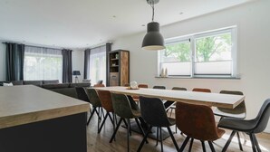 A modern dining area with a long wooden table, multiple chairs, and a hanging light fixture. - Group House in Lemele Near Heuvelrug (Lemele)
