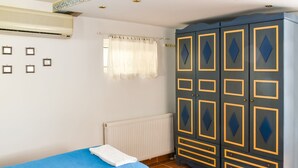 Quarto com duas camas, um guarda-roupa, um radiador e uma janela com cortinas.