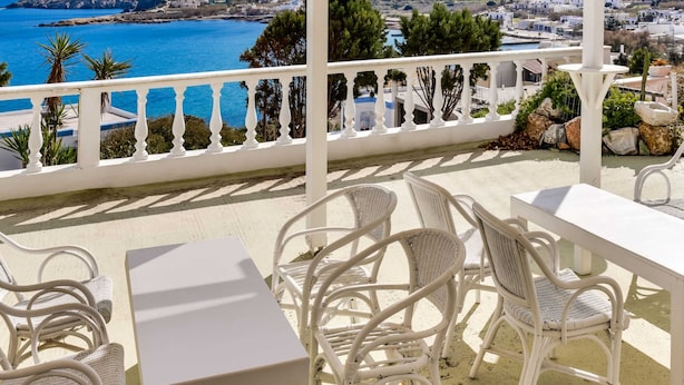 A terrace with white wicker furniture and a view of a coastal town and sea. - Alluring Holiday Home in Syros With Barbecue (Syros)
