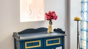 A blue and yellow desk with two drawers, a vase with pink flowers, and a window with a decorative pattern. - Alluring Holiday Home in Syros With Barbecue (Syros)