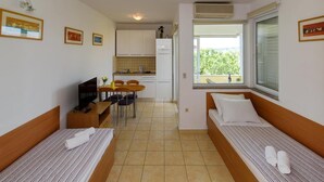 A compact hotel room with two single beds, a small kitchenette, a dining area, and a window with a view. - Alluring Apartment in Sukošan near Sea (Sukosan)