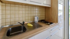 A modern kitchen with white cabinets, a stainless steel sink, a kettle, and a stove. - Alluring Apartment in Sukošan near Sea (Sukosan)