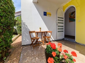 A reception area with a table and chairs, a potted plant with red flowers, and a sign indicating the reception.