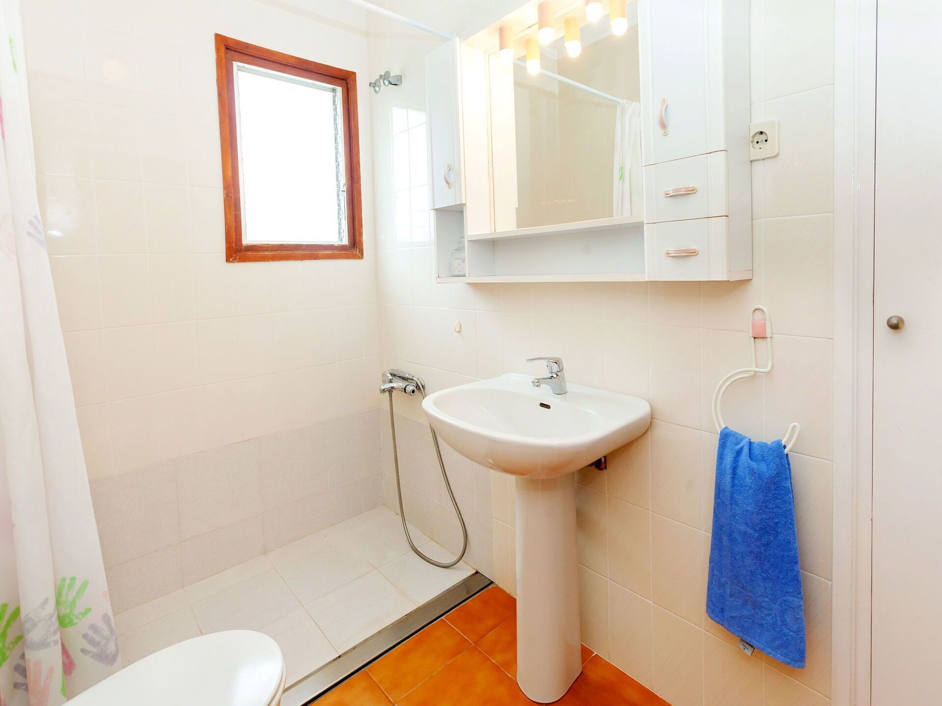 A bathroom with a white sink, a mirror, a shower, and a window.