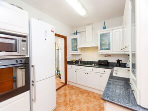 A modern kitchen with white cabinets, a black countertop, and a tiled floor.