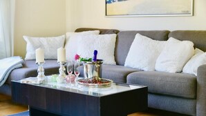 A living room with a dark coffee table, a grey sofa with white cushions, and a painting on the wall. - White House Ferienwohnung Foehr (Alkersum)