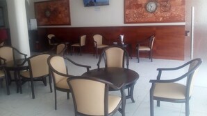 Un restaurant au décor moderne, avec un mur en bois orné d’une horloge et un téléviseur fixé au-dessus d’un espace détente comprenant des tables et des chaises.