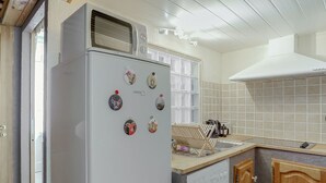Een compacte keuken met een ingebouwde koelkast, een wasmachine en een betegelde spatwand.