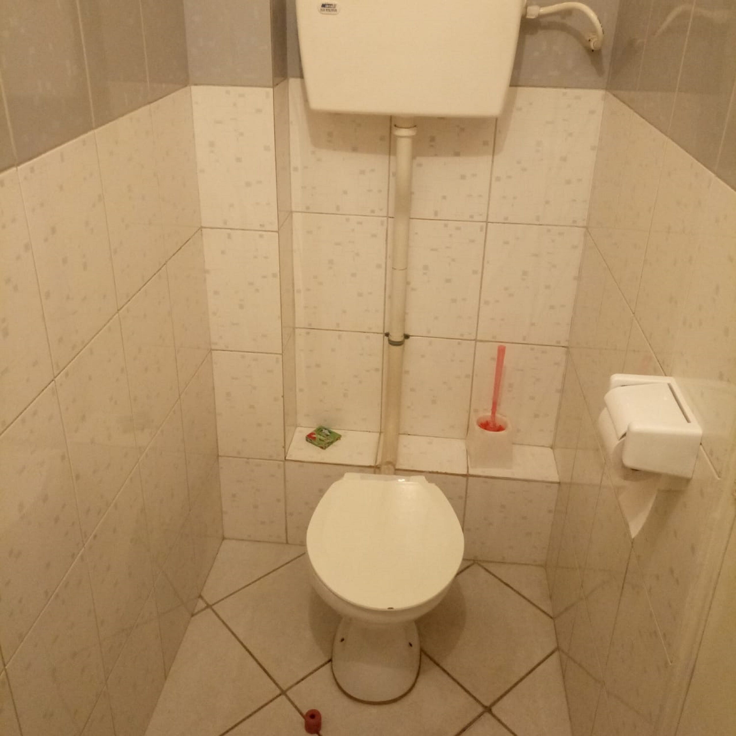 Een kleine betegelde badkamer met toilet, bidet en handdroger.