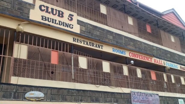 A multi-story building with signs for 'Club 5 Building', 'Restaurant', 'Rooms', 'Conference Hall & Parking', 'S.K. Electronics', and 'Vee Muchandu Electricals'. - Club 5 Restaurant (Nakuru)