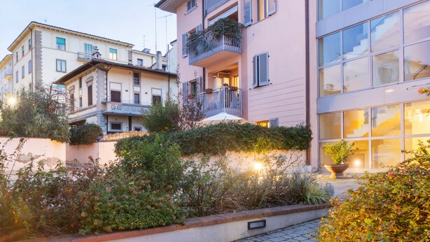 Un edificio de varios pisos con balcones, un patio empedrado y una planta en maceta.