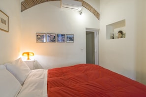 A bedroom with a bed, a lamp, and four framed pictures on the wall.