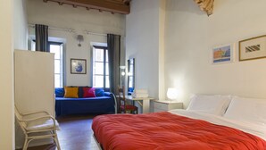 A bedroom with a large bed, a chair, a desk, and a sofa. - Florence City Center Flat Via Dei Neri (Florence)