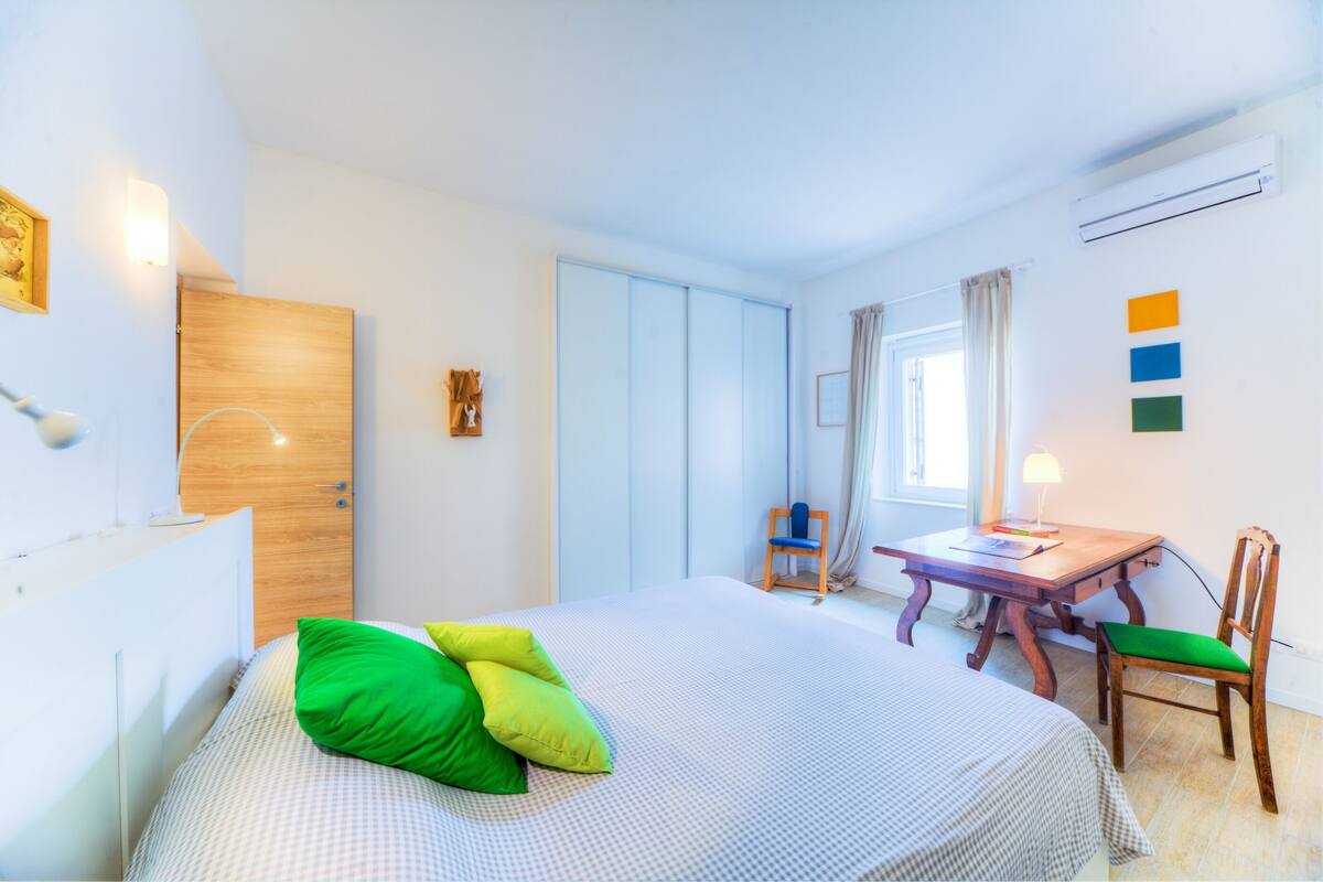 Un dormitorio con cama, escritorio, silla y armario.