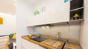 A compact kitchen with white cabinets, a wooden countertop, and a built-in stove.