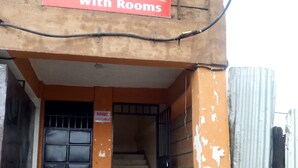 A staircase leading to a building entrance with a sign indicating rooms are available. - Club Settlers (Nakuru)