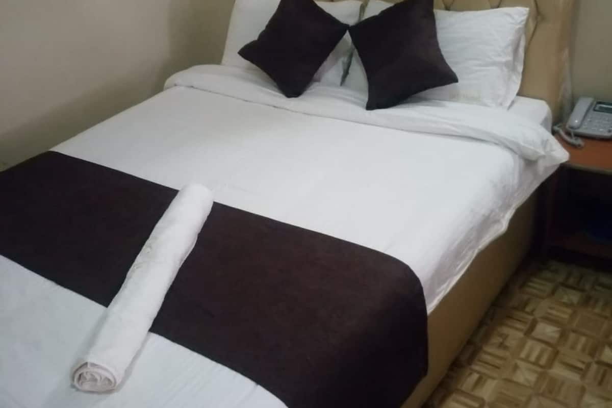 A neatly made bed with a white and brown bedspread, two black pillows, and a white blanket.