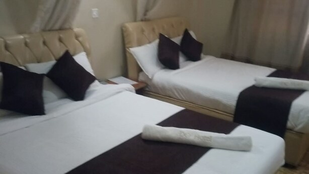 Deux lits avec des draps blancs, des têtes de lit marron foncé et des oreillers assortis.
