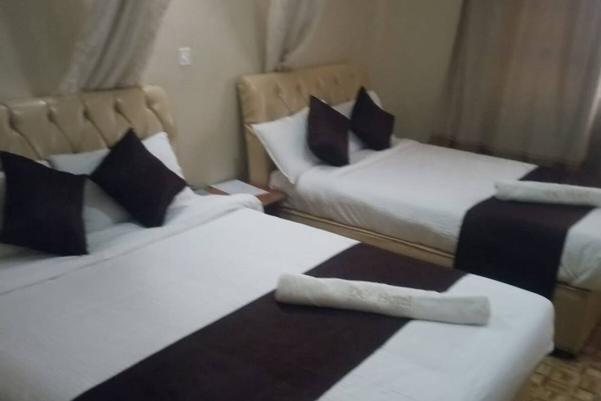 Two beds with headboards, white bedding, dark brown headboards, and dark brown bedspreads.