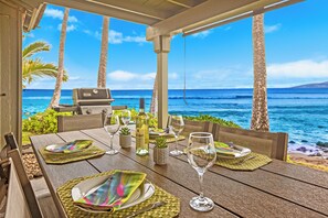 A wooden table set for dining with a view of the ocean and palm trees.