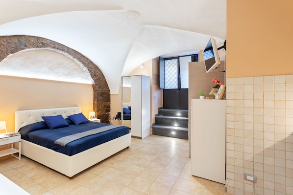 Camera da letto moderna con un letto grande, una scrivania e una scala che conduce a un livello superiore.