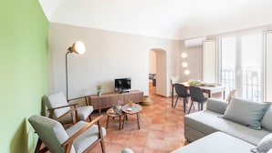 Un salon moderne comprenant un canapé, des fauteuils, une table basse, un téléviseur et un coin repas avec des chaises et une table.