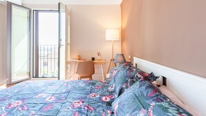 Une chambre d’hôtel équipée d’un lit, d’un bureau, d’une chaise, d’une lampe et offrant une vue sur l’extérieur.