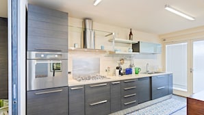 Une cuisine moderne avec des meubles gris, des appareils en acier inoxydable et un tapis à motifs bleus.