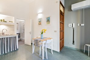 Una cocina moderna con un lavamanos integrado, una zona de comedor con mesa y sillas, y un área de ducha.