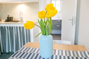 Un jarrón azul con flores amarillas sobre una mesa a rayas en una cocina moderna.