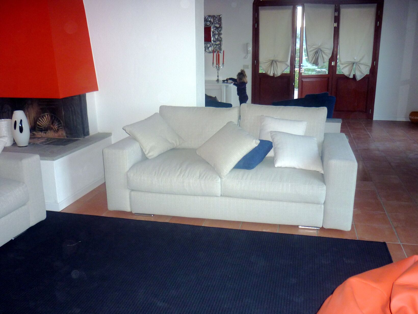 Un salon avec un canapé blanc, une lampe rouge et une cheminée.