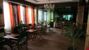 A restaurant with wooden tables and chairs, large windows with curtains, and a chandelier. - Kape Samaritan Guest House (Makutano)