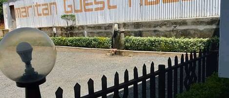 Señal de 'Maritan Guest House' con una cerca de piquetes negros y un farol en primer plano.